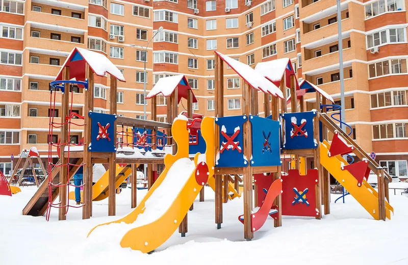 Фото: детская площадка, окруженная высотным жилым домом, © Фотобанк Лори